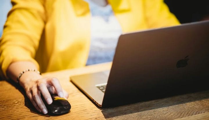 person in yellow dress shirt using black laptop computer