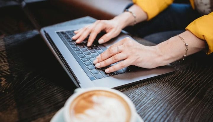 person using macbook pro on brown wooden table