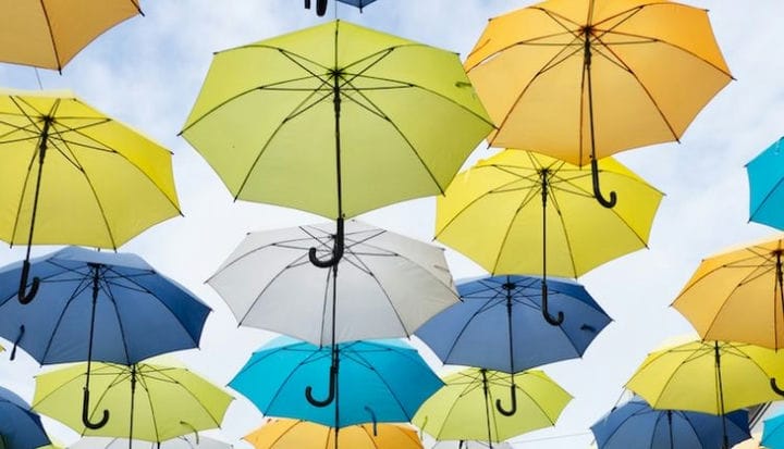 assorted-color umbrella lot under white clouds at daytime